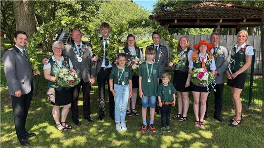 Schützenkönigin Silvia von Holten und Schützenkönig Didi Reimers (Zweite und Dritter von links) stellen sich mit ihrem Hofstaat für ein Gruppenfoto im Freien auf.