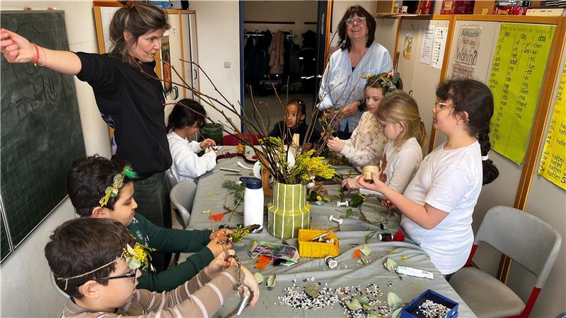 Schulleiterin Sabine Wolff-Stamer (hinten) bestaunt die Kränze im Haar der Kinder. Die haben sie selbst gemacht - mit Unterstützung von Blumendesignerin Caro (links).