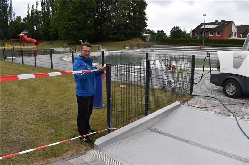 Schwimmmeister Martin Vieweg sperrt die große Liegewiese und den Spielplatz des Freibads in Horneburg mit einem Flatterband ab. Foto: Vasel