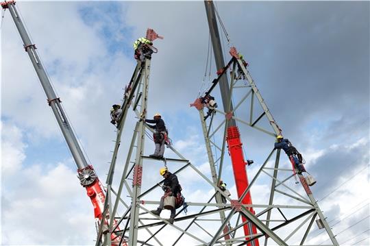 Schwindelfreie Facharbeiter stellen einen neuen, 70 Meter hohen Strommast auf. Fotos: Tennet