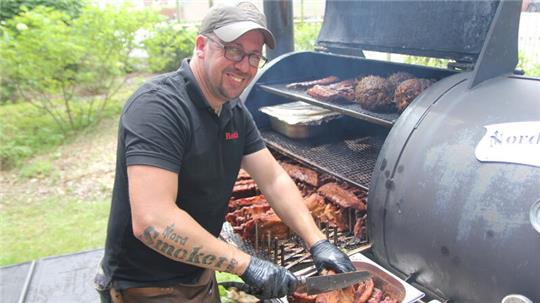 Sebastian Jakubowski, der von allen nur „Basti“ genannt wird, bereitet hier Spareribs am Smoker vor und zeigt seine Leidenschaft für Nord Smoker BBQ durch seine Tätowierung am Unterarm.