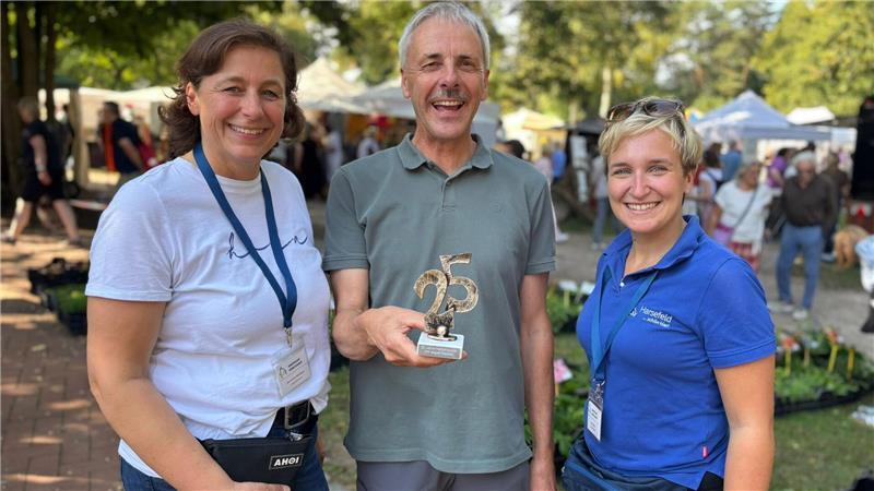 Seit 25 Jahren dabei: Staudenhändler Burkhard Tiedemann erhielt für seine Treue einen kleinen Pokal von Susanne Nettkau (links) und Lea Stölpe vom Stadtmarketing Harsefeld.