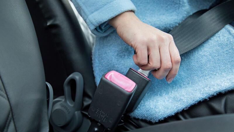 Eine Frau legt im Auto den Gurt an.