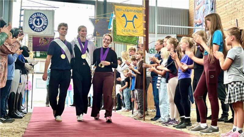 Sie sicherten die internationalen Erfolge 2025: Junioren-Weltmeister Henry Frischmuth, Kathrin Meyer und Gesa Bührig auf dem roten Teppich in der Voltigierhalle in Fredenbeck.