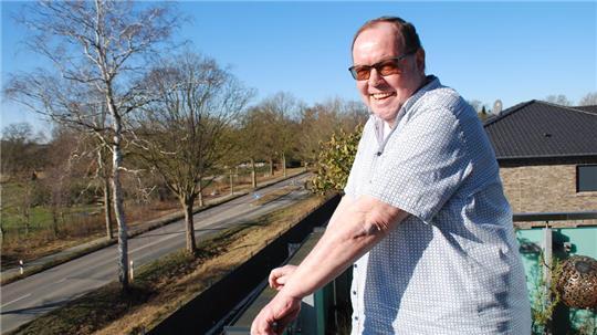 Siegfried Stresow auf seinem Balkon mit Blick auf den Beekhoff, der hinter den Bäumen liegt.