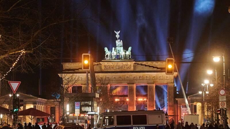 Angriffe auf Polizei, Hunderte Festnahmen in Berlin Silvester in Berlin: Polizeiwagen stehen vorm angestrahlten Brandenburger Tor.