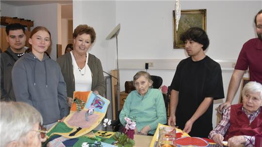Sina-Laureen Strohmaier und BBS-Lehrerin Angela Quast erklären den Senioren die Nesteldecken.