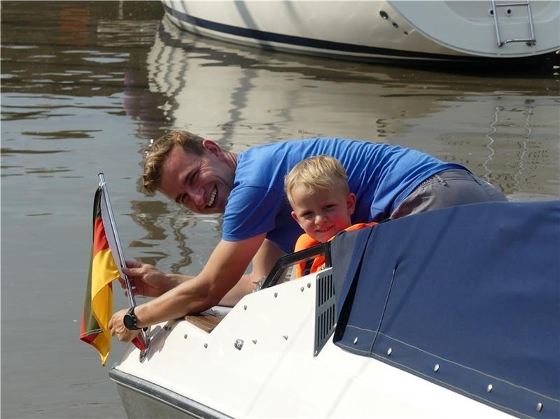 Skipper-Neuling Sebastian Cordes aus Borstel schraubt am neuen Boot die Flagge ab; Neffe Fiete (5) findet das alles ziemlich spannend.