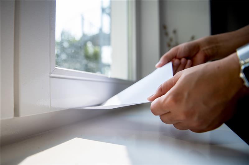 So findet man heraus, ob ein Fenster dicht ist: Ein eingeklemmtes Blatt Papier sollte fest sitzen. Lässt es sich herausziehen, müssen die Dichtungen erneuert werden. Foto: Zacharie Scheurer/dpa