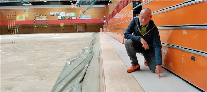 Horneburger Sporthalle bekommt einen hellgrauen Sandwichboden So sieht der neue Sandwichboden aus: Bauamt-Mitarbeiter Michael Scholz zeigt auf den hellgrauen Bodenbelag bei der Tribüne. Foto: Lohmann