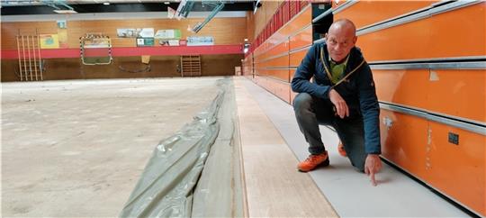 So sieht der neue Sandwichboden aus: Bauamt-Mitarbeiter Michael Scholz zeigt auf den hellgrauen Bodenbelag bei der Tribüne. Foto: Lohmann