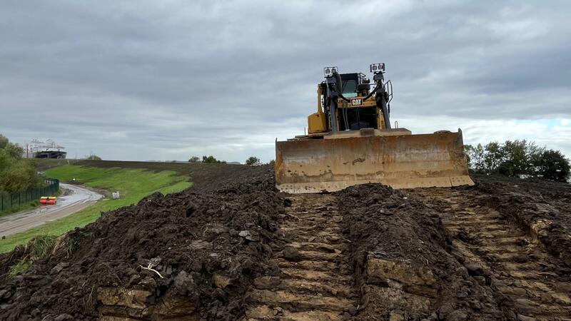 Elbdeich im Alten Land wird zehn Jahre zur Baustelle So wird es zehn Jahre lang zwischen dem Lühe-Anleger und Schöpfwerk Twielenfleth aussehen: Die Raupe modelliert hier satellitenunterstützt den neuen Deich in Stadersand, im Hintergrund liegt das schwimmende LNG-Terminal.