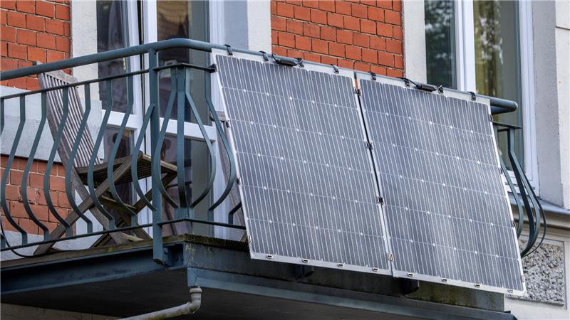 Solarmodule für ein sogenanntes Balkonkraftwerk hängen an einem Balkon.