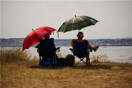 Sonnenschutz ist besonders wichtig: Neben Sonnencreme und leichter Kleidung kann auch ein Sonnenschirm helfen. Foto: Ben Birchall/PA Wire/dpa