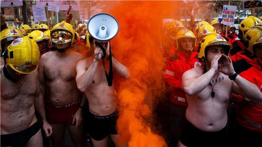 Spanische Feuerwehrleute demonstrieren in Badehosen in Barcelona. 