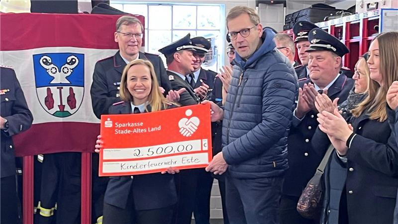 Sparkassen-Vorstand Jan Schuback überreicht der Kinderfeuerwehrwartin Madeleine Bahr von der Kinderfeuerwehr Este einen Scheck zur Gründung.