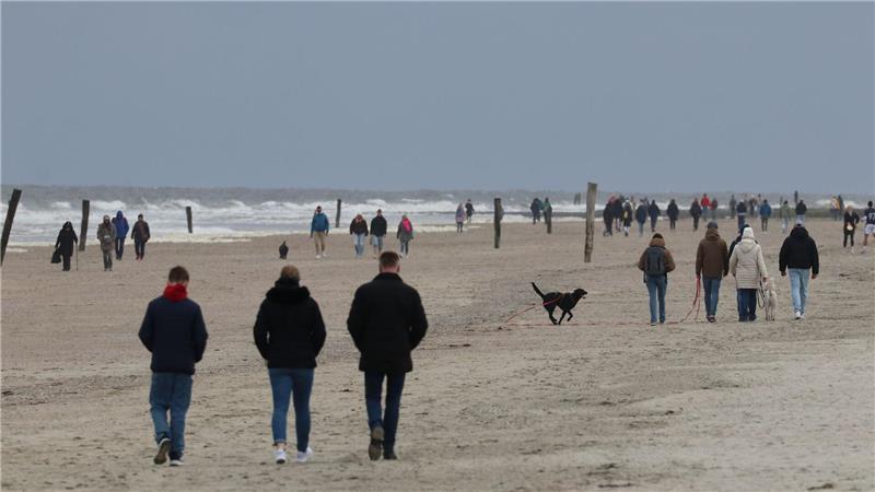 Urlauber entspannen an Ostertagen auf Norderney Spaziergänger am Strand der ostfriesischen Insel Norderney.