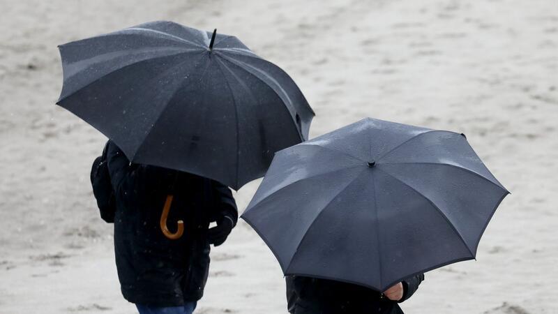 Spaziergänger gehen bei Wind und Regen spazieren.