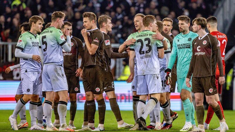 Spieler beider Mannschaften stehen nach dem Abpfiif auf dem Platz.