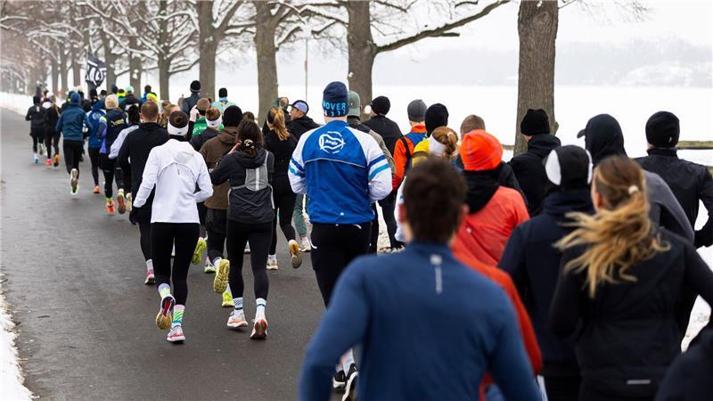 Sportfans laufen bei Winterwetter um den Maschsee in Hannover.