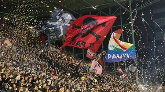 St. Pauli-Fans schwenken vor dem Spiel Fahnen.