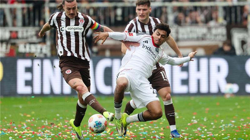 St. Paulis Kapitän Jackson Irvine (l) wird von Frankfurts Nathaniel Brown gestört.
