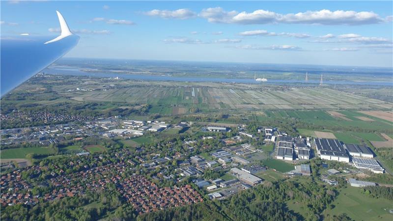Ein Segelflieger fliegt über Stade. Links oben ist ein Flügel eines Segelfliegers zu sehen. 