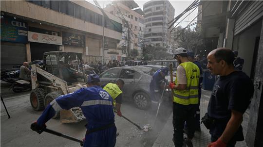 Städtische Arbeiter räumen Trümmer von einer Straße neben einem Wohnhaus, das bei dem israelischen Luftangriff am Sonntag (23.11.2025) beschädigt wurde, bei dem der Generalstabschef der Hisbollah, Haitham Ali Tabatabai, getötet wurde.