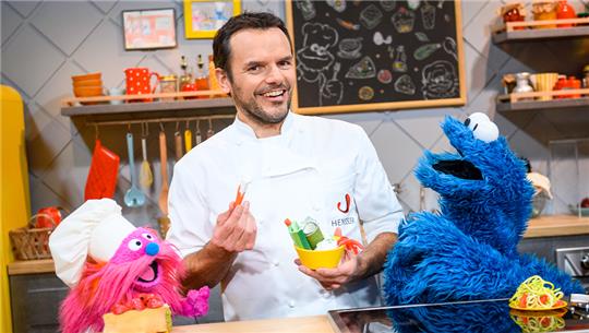 Steffen Henssler kocht demnächst mit den Puppen "Gonger" (links) und "Krümelmonster" bei RTL+, und Super RTL. Foto: Jonas Walzberg/dpa