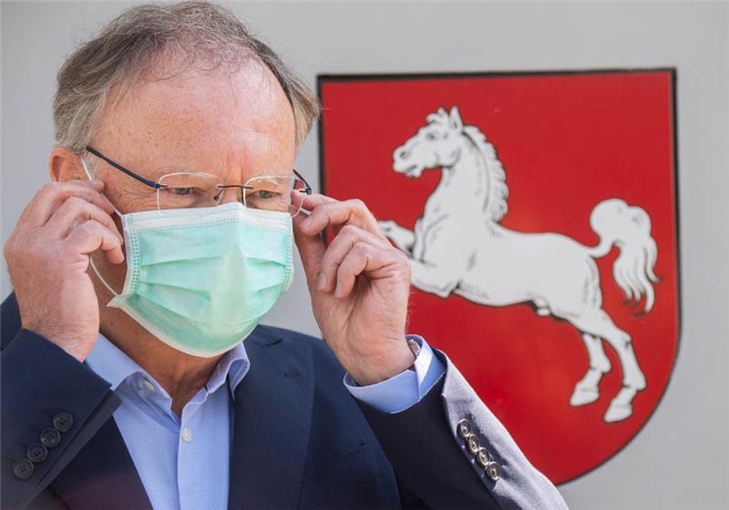 Stephan Weil (SPD), Ministerpräsident Niedersachsen, steht vor der Staatskanzlei und zieht einen Mundschutz an. Foto: Julian Stratenschulte/dpa