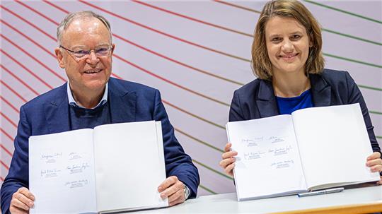 Stephan Weil (SPD) und Julia Willie Hamburg (Bündnis 90/Die Grünen) zeigen den Koalitionsvertrag von SPD und Grünen in Niedersachsen, nachdem sie diesen unterzeichnet haben. Foto: Moritz Frankenberg/dpa