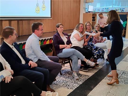 Stiftungsvorständin Barbara Pampe (stehend) übergibt den symbolischen Staffelstab an Hortleiterin Karina Klingbeil (links) und Schulleiterin Yvonne Lawes.