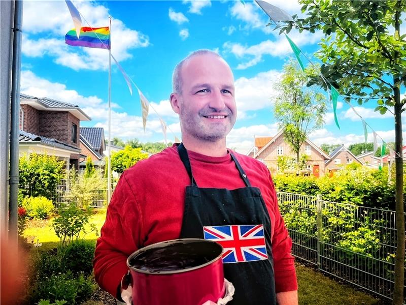 Stolzer Papa mit selbstgemachtem Kuchen und Regenbogenflagge im Garten: Kai Koeser .