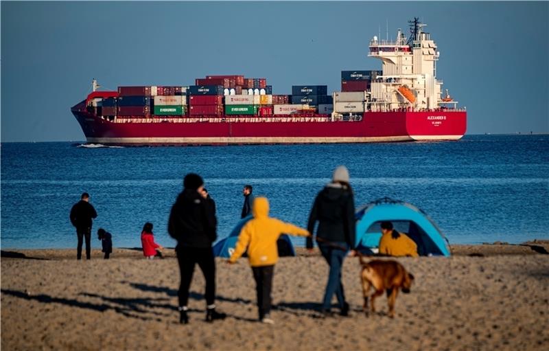 Strandspaziergänger schauen auf den Containerfrachter „Alexander B“. Foto: Axel Heimken/dpa