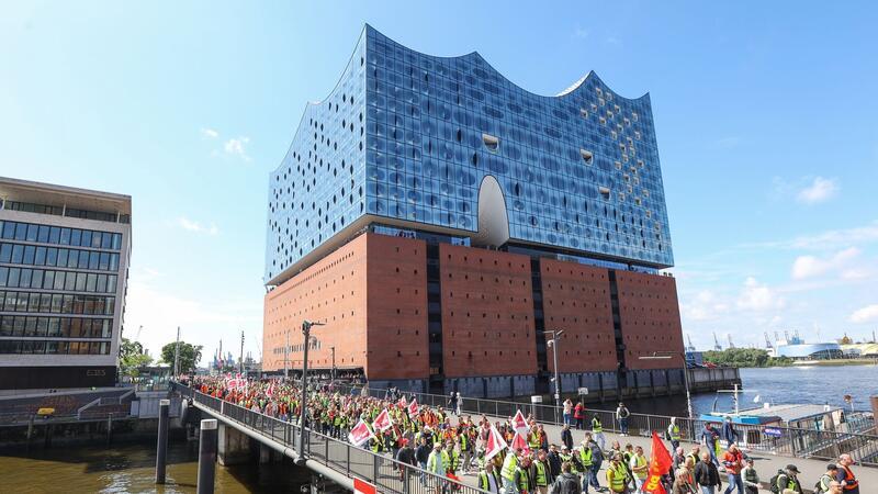 Streikende Hafenarbeiter ziehen bei einer Demonstration an der Hamburger Elbphilharmonie entlang.