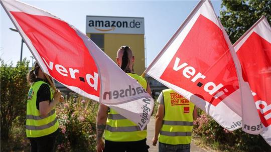 Streikende stehen mit Fahnen von Verdi vor einem Verteilzentrum des Online-Händlers Amazon in Leipzig. (Archivbild)