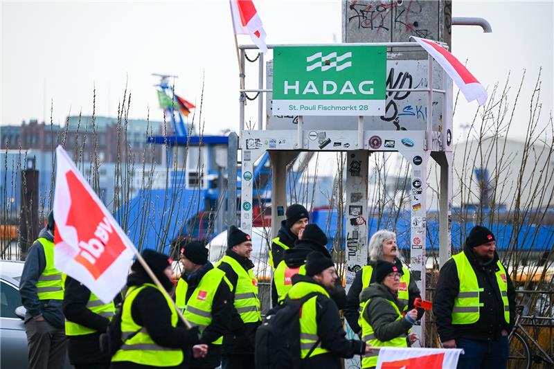 HVV: Totalausfall beim Fährverkehr der Hadag Streikende stehen mit Warnwesten und Fahnen vor stillliegenden Fähren am Hadag-Anleger. Foto: Jonas Walzberg/dpa