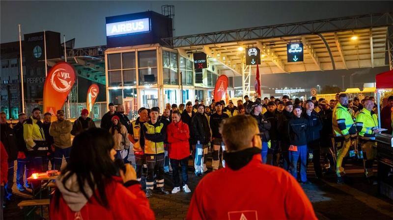 Streikende stehen vor dem Werksgelände von Airbus in Finkenwerder