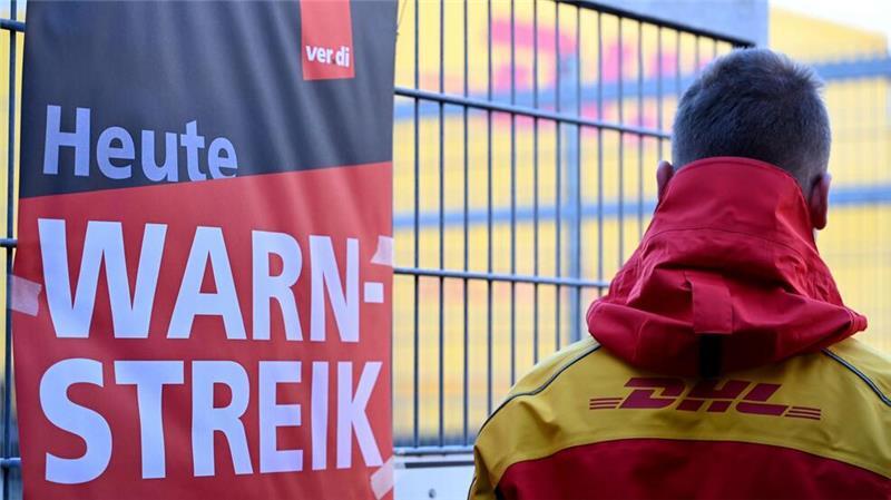 Millionen Sendungen bleiben wegen Post-Warnstreiks liegen Streikposten am Werkstor: Ein DHL-Mitarbeiter hat die Arbeit niedergelegt und schaut auf eine Zustellbasis, in der er sonst arbeitet.