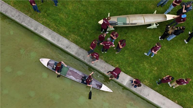 Studenten und Studentinnen der Bauhaus-Universität Weimar fahren mit dem Betonkanu auf dem Wasser im Weimarer Schwanseebad. (Aufnahme mit einer Drohne)