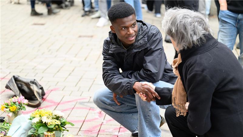 Suraj Mailitafi (l) von der Initiative „Gerechtigkeit für Lorenz“ spricht mit einer Passantin an dem Ort, an dem der 21-Jährige von der Polizei erschossen wurde.  