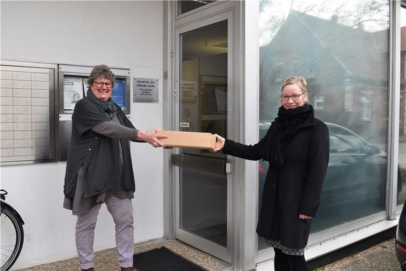 Susanne Höft-Schorpp reicht vor dem Altländer Archiv einen Karton mit Archivalien an ihre Nachfolgerin Dr. Kai Rump weiter (von links). Foto: Vasel