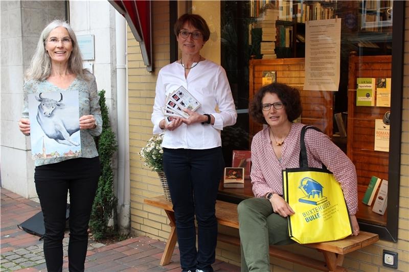 Susanne Weggen (von links) mit ihrem Bullen-Aquarell „OH!“, Rita Körner mit den Postkarten-Sets und Melanie Hainke vom Team des Buxtehuder Bullen. Foto: Frank