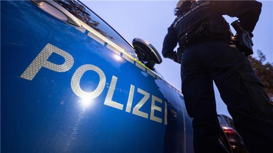 Eine Polizistin steht neben einem Polizeifahrzeug. (zu dpa: «Schüsse aus Autokorso - Polizeieinsatz in Bremen»)
