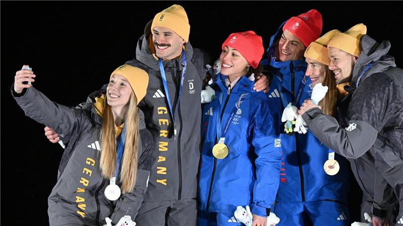Tabitha Stoecker (Großbritannien) und Matt Weston (Großbritannien, beide M) posieren bei der Siegerehrung ihren Goldmedaillen nach dem Skeleton-Team-Wettbewerb neben Susanne Kreher (Deutschland, l) und Axel Jungk (Deutschland, 2.v.l.) mit der Silbermedaille und Jacqueline Pfeifer (Deutschland, 2.v.r.) und Christopher Grotheer (Deutschland) mit der Bronzemedaille bei den Olympischen Winterspielen Mailand Cortina 2026.