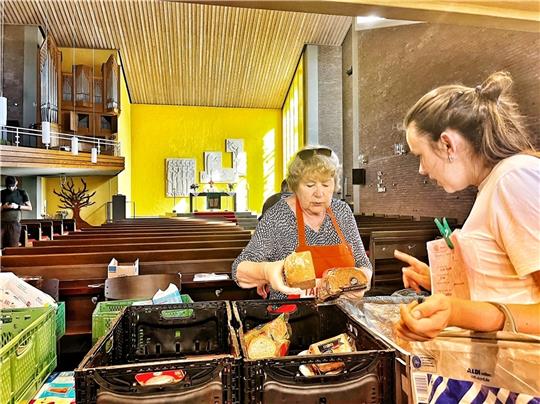 Tafel-Mitarbeiterin Gisela Pohl (links) zeigt der 21-jährigen Irina, welche Sorten Brot heute an der Ausgabe in St. Markus zu haben sind. Foto: Richter