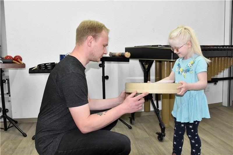 Teamer Iden Kjeld lässt die fünfjährige Teresa beim Instrumentenkarussell verschiedene Instrumente testen.