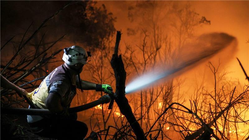 Teams des syrischen Zivilschutzes und Freiwillige bekämpfen am frühen Morgen des 12. Juli den zehnten Tag in Folge die Flammen eines Waldbrandes in der Nähe der Stadt Kasab in der syrischen Provinz Latakia.