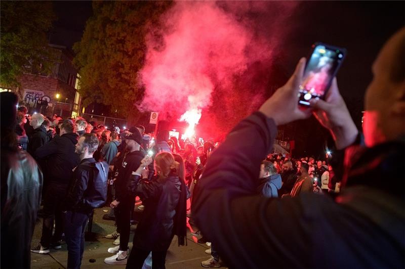 Teilnehmer der Demonstration "Klassenfest gegen Staat und Kapital" am Bahnhof Sternschanze fotografieren in der Menschenmenge gezündete rote Bengalos. Die Polizei war mit deutlich weniger Kräften im Einsatz als in vergangenen Jahren. Zwischenfälle gab es bis zum Abend nicht. Foto: Jonas Walzberg/dpa