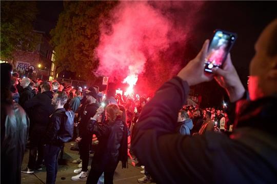 Teilnehmer der Demonstration "Klassenfest gegen Staat und Kapital" am Bahnhof Sternschanze fotografieren in der Menschenmenge gezündete rote Bengalos. Die Polizei war mit deutlich weniger Kräften im Einsatz als in vergangenen Jahren. Zwischenfälle gab es bis zum Abend nicht. Foto: Jonas Walzberg/dpa